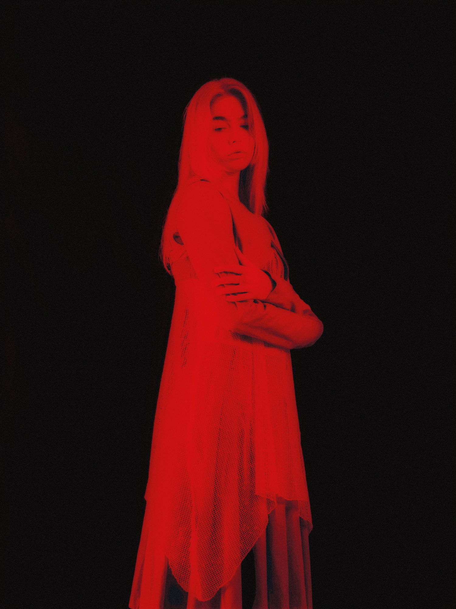 Portrait d'une femme baignée de lumière rouge sur fond noir