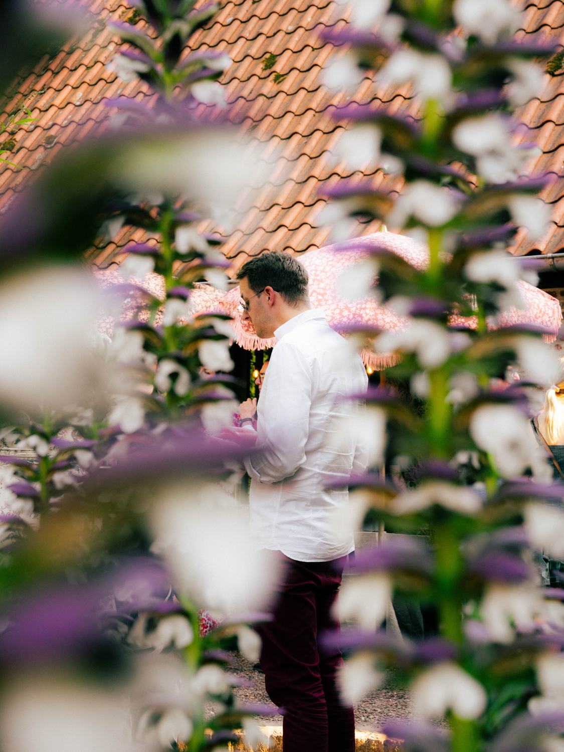 Homme en chemise blanche vu à travers des fleurs mauves