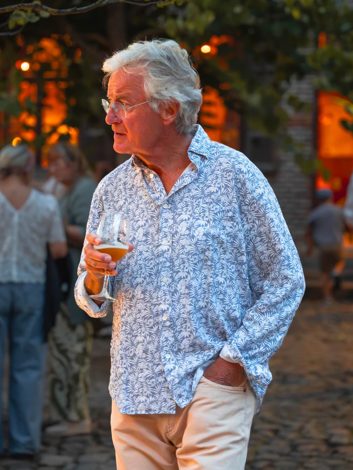 Invité à la chemise fleurie tenant un verre de bière