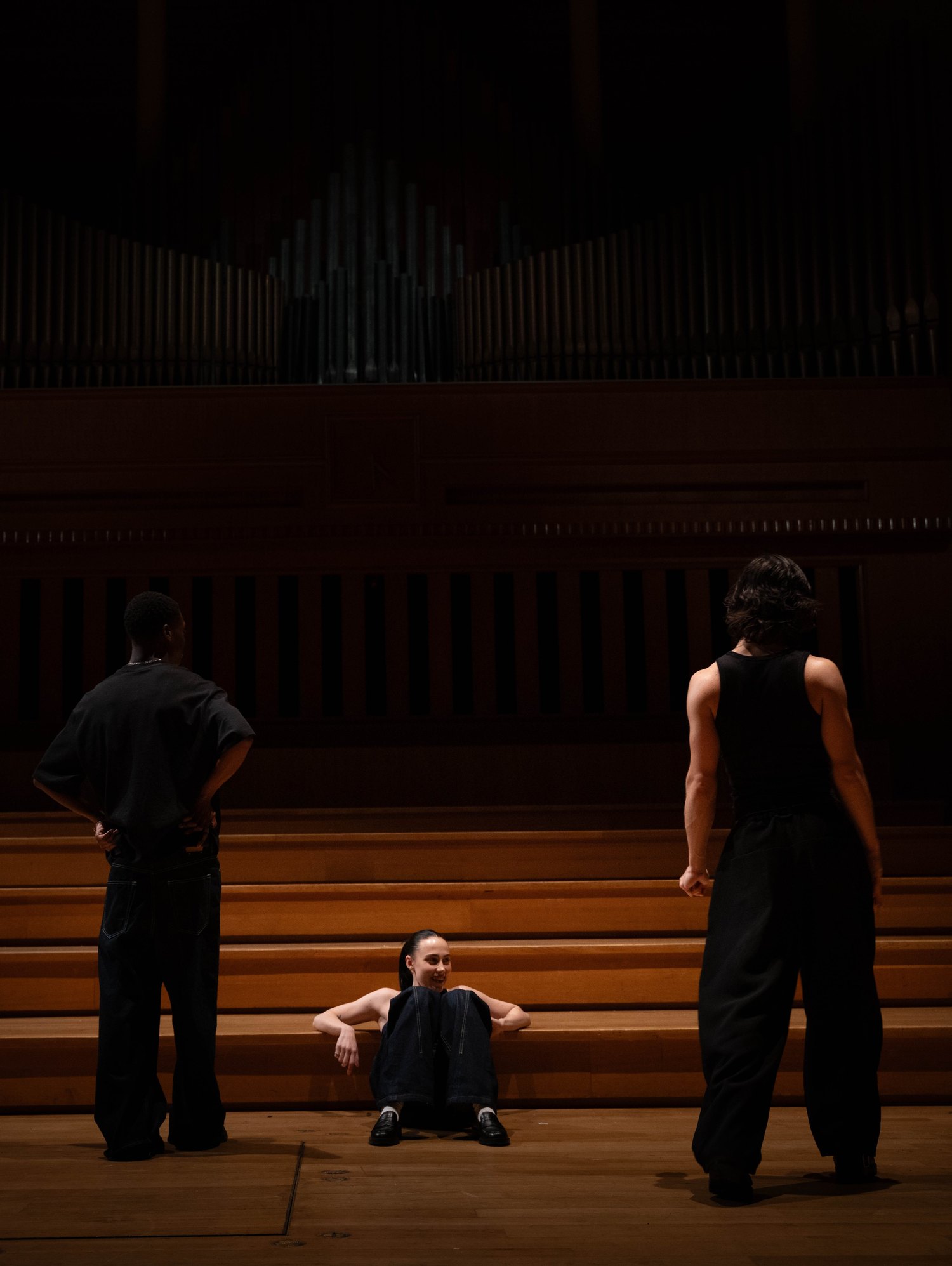 Trois danseurs sur la scène d'une grande salle, devant un orgue