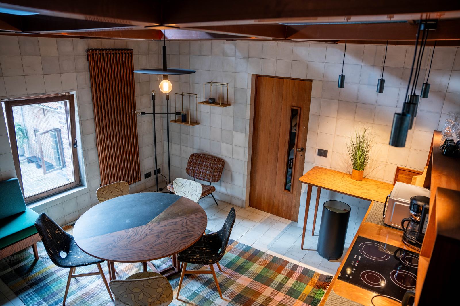 Cuisine et salle à manger avec table ronde, carrelage clair et plafond en bois