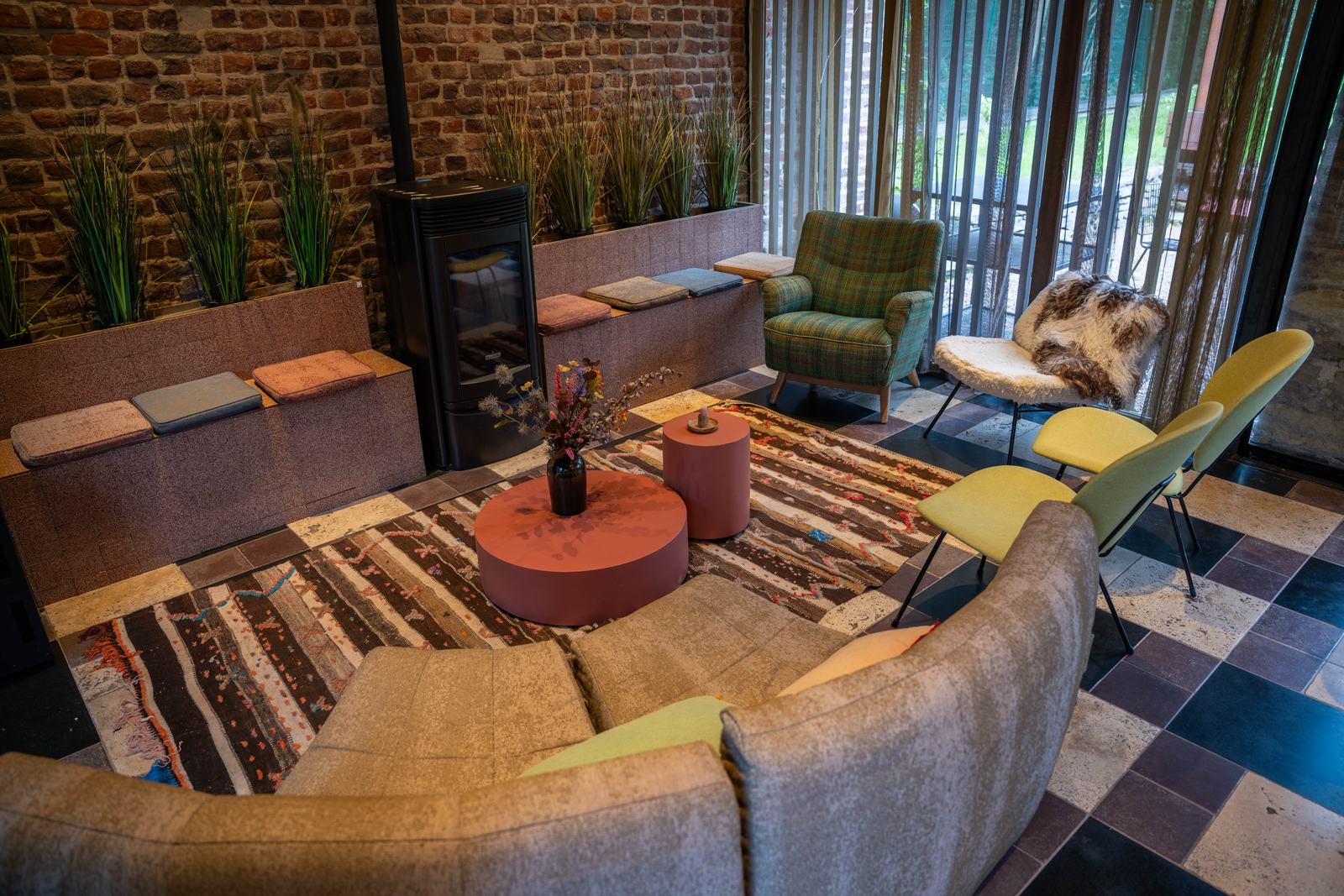 Coin salon avec poêle, canapé et fauteuils colorés