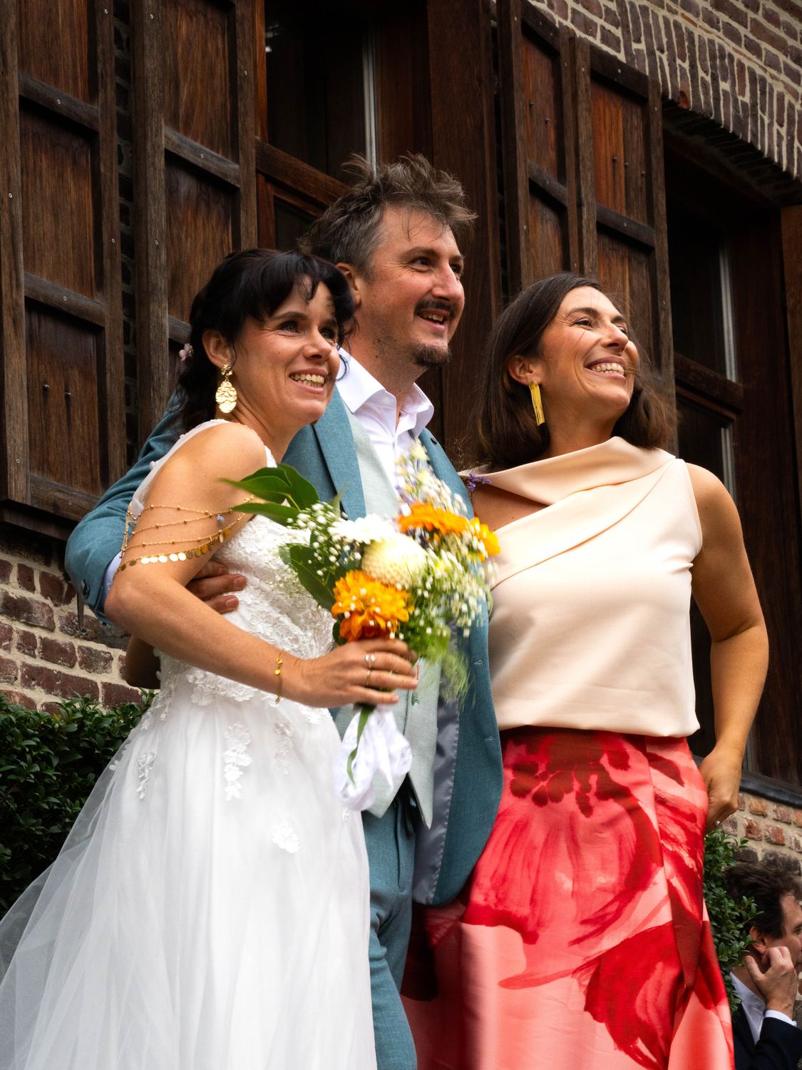 Les mariés et une invitée souriants, en couleur