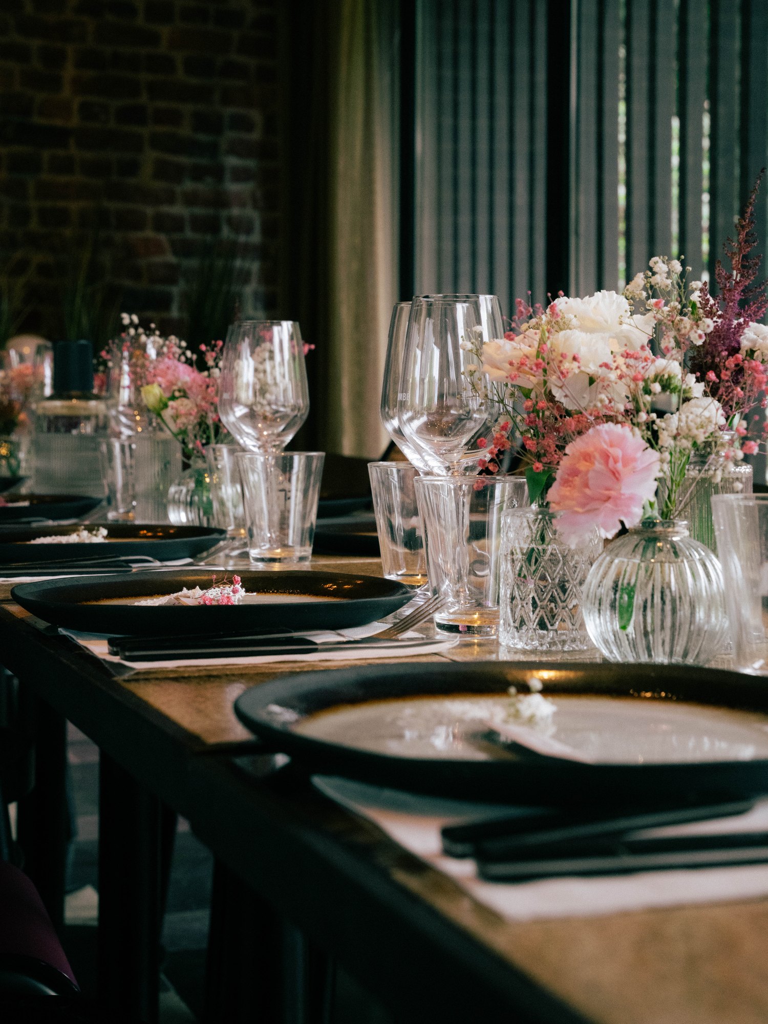 Table de réception dressée, verres et bouquets de fleurs roses