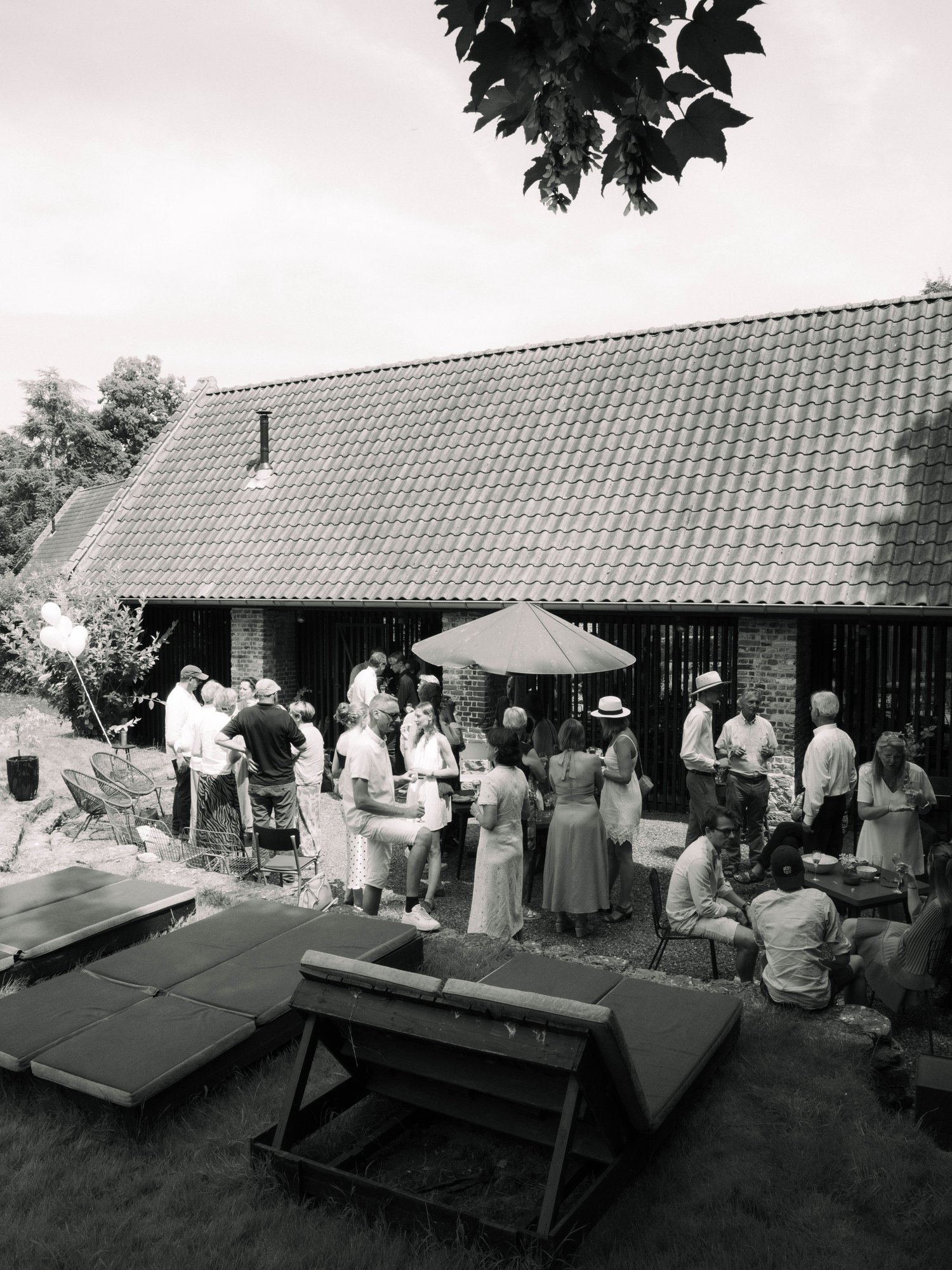 Invités réunis dans le jardin devant la grange, en noir et blanc